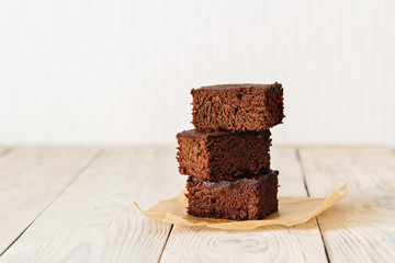 Brownie, chocolate cake on a light rustic wooden table