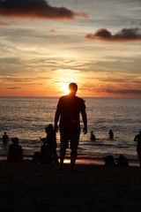silhouette of a man walking along the seashore at sunset