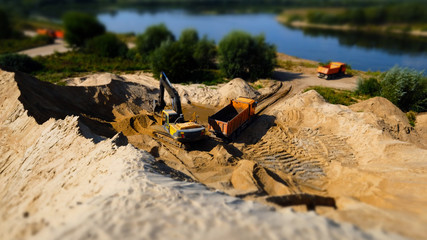 Excavator loading sand into dumper truck