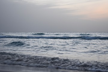 Naklejka na ściany i meble Waves are hitting the beach in the evening before sunset