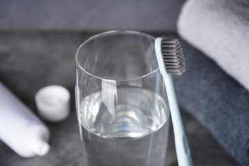 Toothbrush, glass of water and towels on a gray background, close-up. Dental and healthcare concept.
