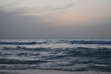 Waves are hitting the beach in the evening before sunset