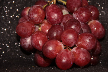 Clusters of grapes on a black shiny background.