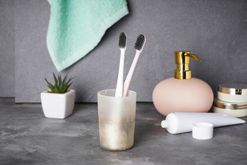 Two toothbrushes in a glass on a gray background. Dental and morning concept.