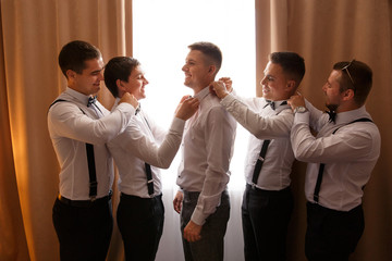 Wedding photo about helping of the groomsmen to the groom at wedding day, they put on a bow tie