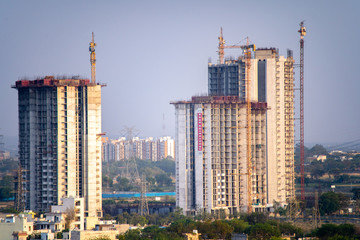 Fototapeta premium Aerial shot of under construction building with multiple floors and crane at the top standing out in the countryside. Shows the rapid development of skyscrapers even in the most rural areas with the