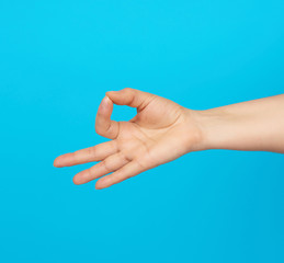 female hand shows the mudra of Knowledge on a blue background