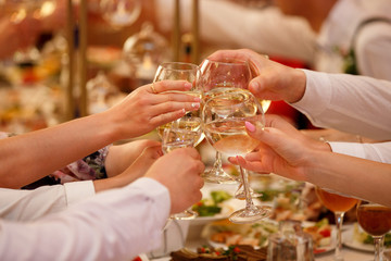 Celebration and holidays concept - hands with wine glasses clinking at party