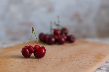Ugly organic fruits - sweet cherries on a brown board. Trends. Ugly food. Copy space. Horizontal orientation.