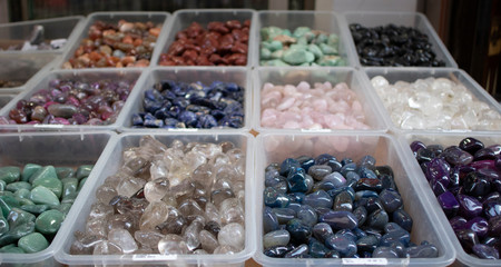 Polished natural stones of different colors and varieties are in the boxes.
