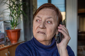 Retired woman on the phone in isolation at home. Elderly female having phone conversation using electronic device