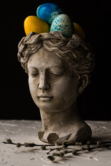 Antique statue of a girl and Easter painted eggs