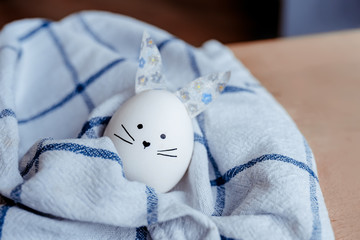 Easter holiday concept with cute handmade egg bunny. Frame with copy space for text. One easter egg background trendy colored classic blue. Minimal style. Funny Easter eggs with different funny faces.