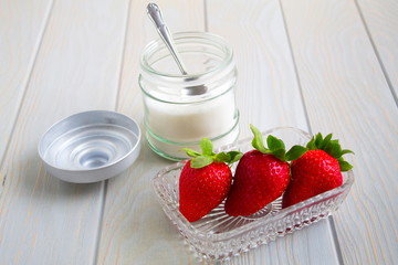 delicious red strawberries next to bowl with sugar and a spoon