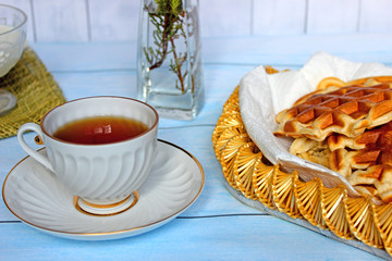 Good morning concept. Hearty and delicious breakfast. Homeliness. A cup of tea with waffles and milk, fresh flowers