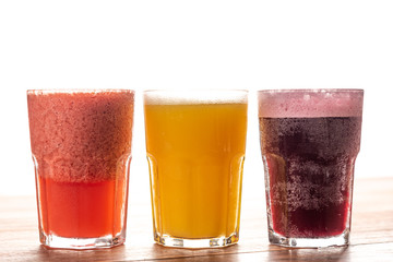 Array of colorful fresh fruit juices served in tall glasses on a wooden background