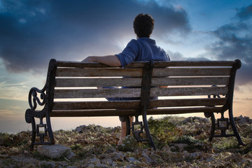 Naklejka na ściany i meble Man sitting on bench overlooking sea