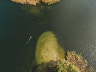 Aerial drone photo of small yacht sailing on lake Ukiel in Olsztyn, Masurian Lake District. Vertical drone view.