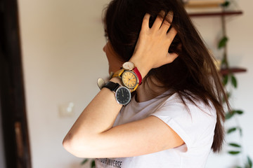 close up portrait of young woman wearing three different hand watches  with different numerals. Black, yellow and read wrist watch. 