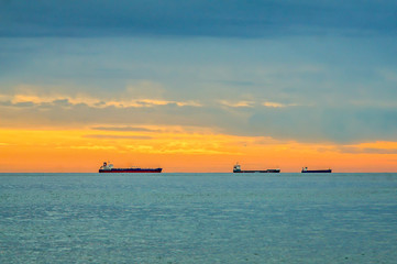 Fototapeta premium Distant Oil Tankers Far on the Horizon of the Mediterranean Sea at Sunset