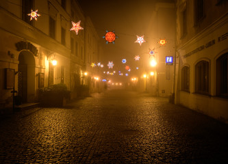 Night view of the colorful streets of the city during dense fog and smog. Winter season, Christmas time with colorful illuminations on the streets. Lublin, Poland, Europe. - obrazy, fototapety, plakaty
