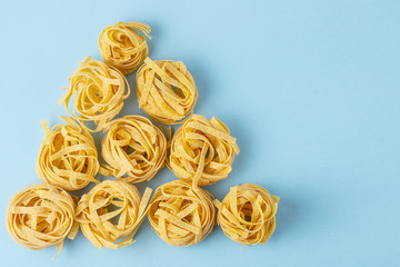 tagliatelle pasta nests on a blue background pyramid Italian food