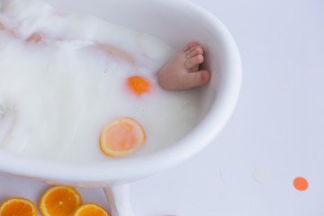 a small child in a bath with milk and oranges