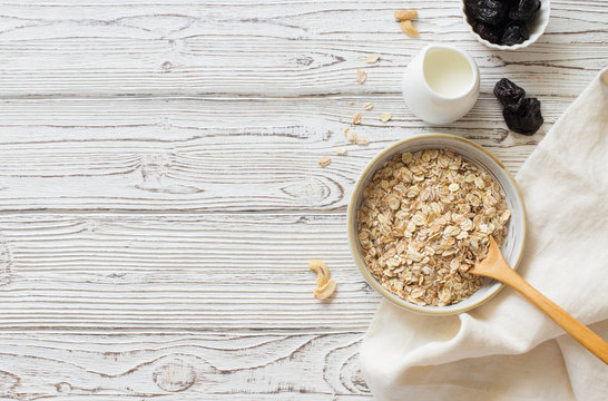 Ingredients for healthy breakfast- oat flakes, dried prunes and milk