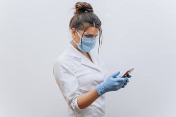 Doctor in mask and glasses with phone in hands. Doctor with phone in hands.