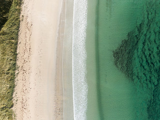 Aerial drone photo of 
a beautiful beach with turquoise water located in the north of Scotland on the North Coast 500 road. Vertical drone look.