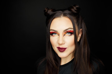 Fototapeta premium Fashion beauty portrait of a beautiful young girl. Makeup cat. Sexy woman with koshachmi ears on the hair. Face of the beautiful woman with long brown hair posing at studio over dark background.