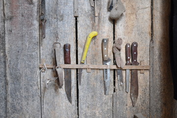 Rail with different knives for carpentry on an old wooden wall