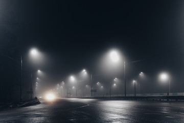 Foggy misty night road illuminated by street lights