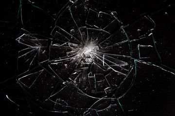 Broken glass on black background with lots of glass splinters and cracks
