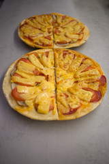 two round pizzas with different fillings, cut in half with cheese, salami with mushrooms and tomatoes