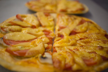 two round pizzas with different fillings, cut in half with cheese, salami with mushrooms and tomatoes
