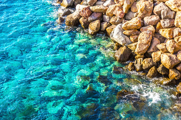 Naklejka na ściany i meble Background made of clear azure and blue ocean water and rocky coastline. View from above
