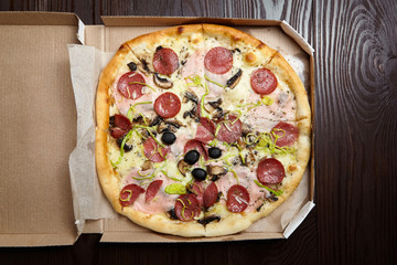 Pizza in a cardboard box on wooden table