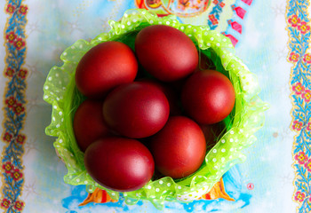 Basket with easter cake and red eggs on rustic wooden table. Top view.