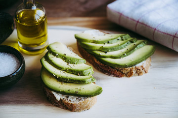 Tartines de pain de campagne avec des lamelles d'avocat assaisonnée à l'huile d'olive et poivre