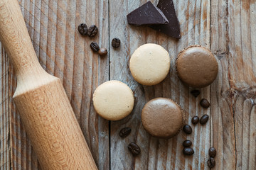 Macarons café et chocolat avec rouleau de patisserie sur une planche en bois