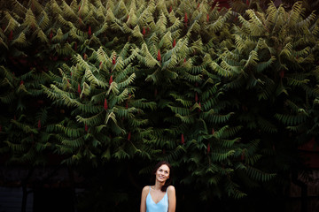 Portrait of a beautiful smiling girl on the background of a huge green bush