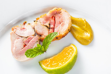 Stuffed chicken rolls on a white plate with mustard