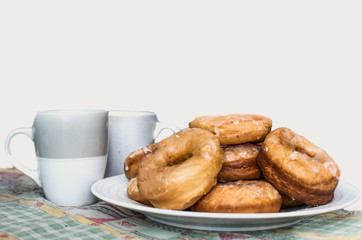 donuts on a white plate and 2 cups of coffee, white background