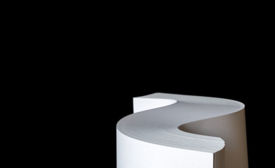 Studio photo of multiple sheets of rolled A4 paper stack (S-shaped ream) on black background. Simple, isolated object with copy space perfect for illustrating various concepts. Selective focus (shallo