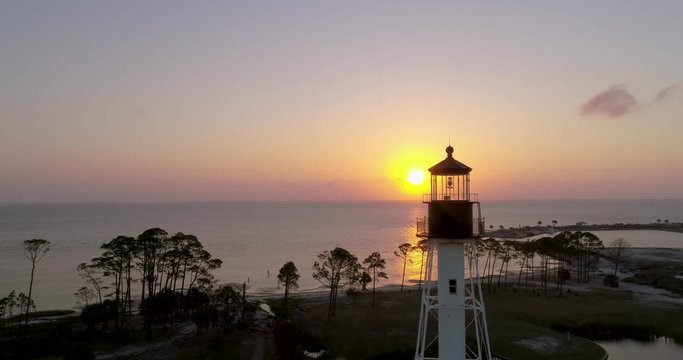Aerial flight around a lighthouse revealing a beautiful sunset