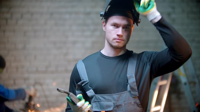 Young handsome man walking in the workshop holding a welding instrument
