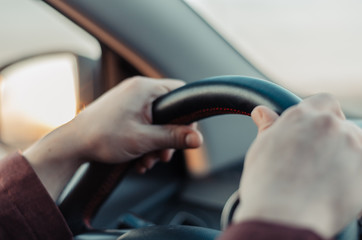Closeup guy hand on car steering wheel