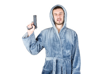 Portrait of young caucasian bearded man in blue bathrobe with black firearm isolated on white...