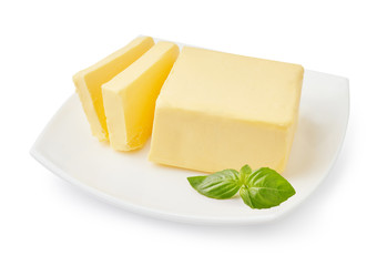 Sliced butter of piece butter on the white plate with basil leaves isolated on white background.